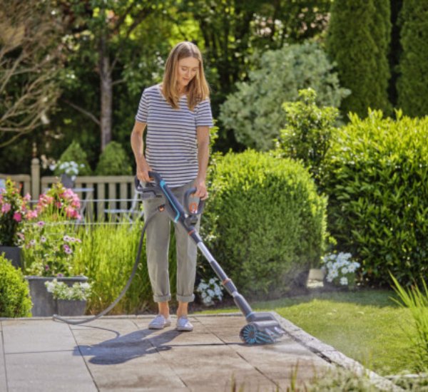 Nainen pesee pihalaatoitusta Gardena AquaBrush Patio -terassipesurilla